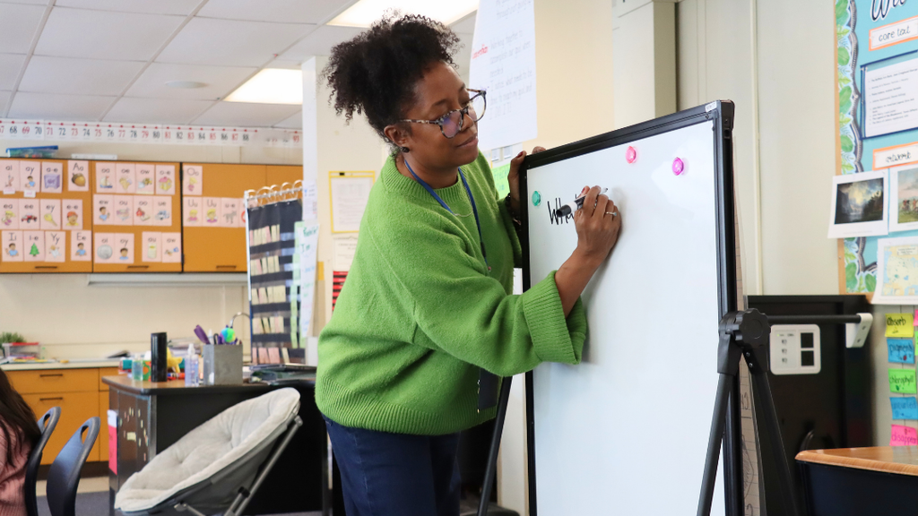 Teacher writing on whiteboard.