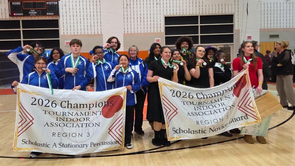 NAHS Band and Color guard pose for large group photo inside gym holding award banners.