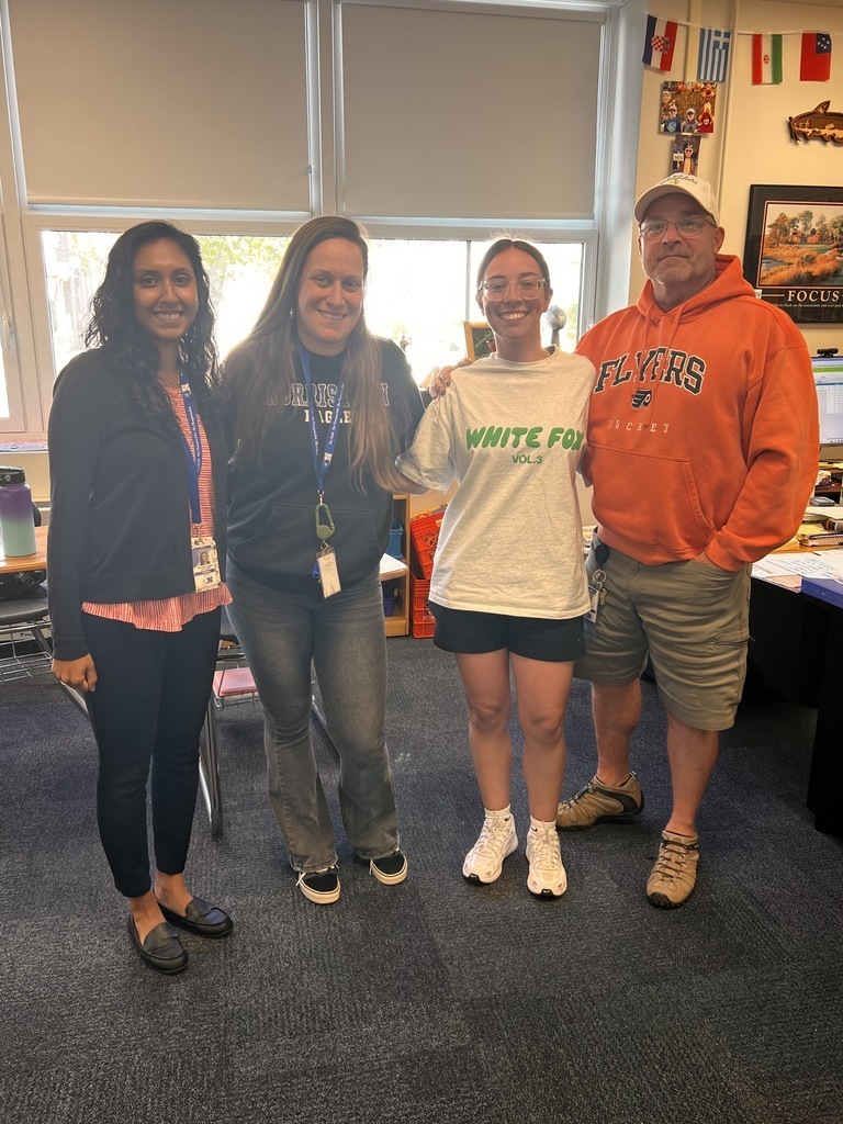Four teachers are posing together in a classroom