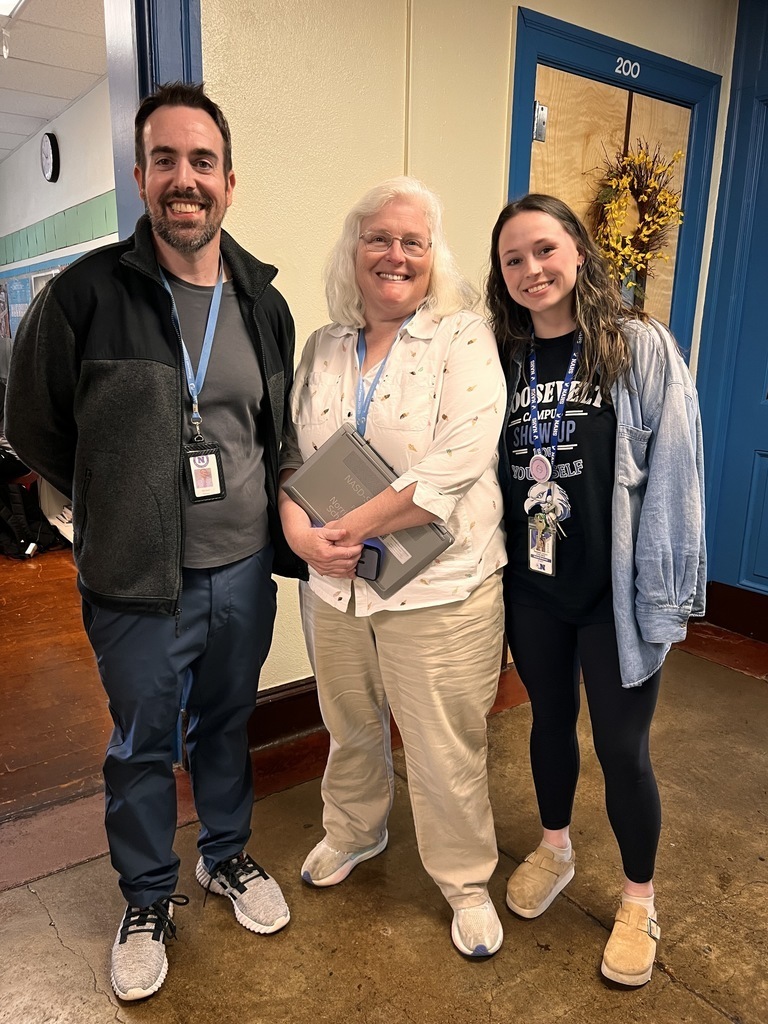 Three teachers are posing together in the hall