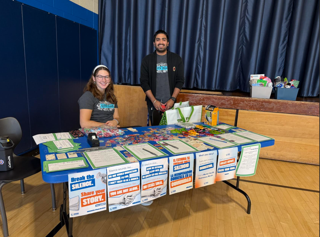 Two members of City Year are at a table ready to help students in the gym