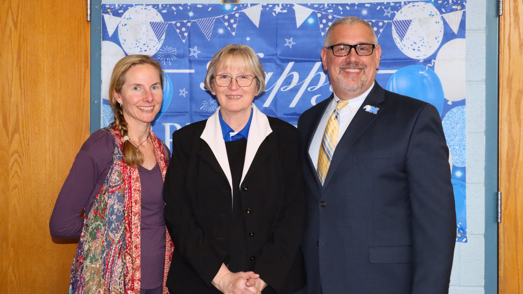 Three NASD staff members pose for photo in front of photo backdrop.