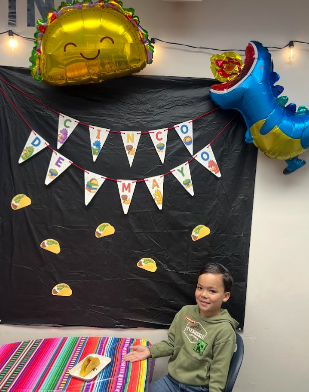 Student sitting in front of Cinco de Mayo sign.