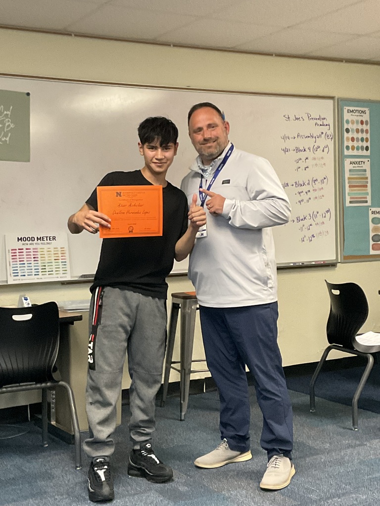 A student is posing with his award and the principal