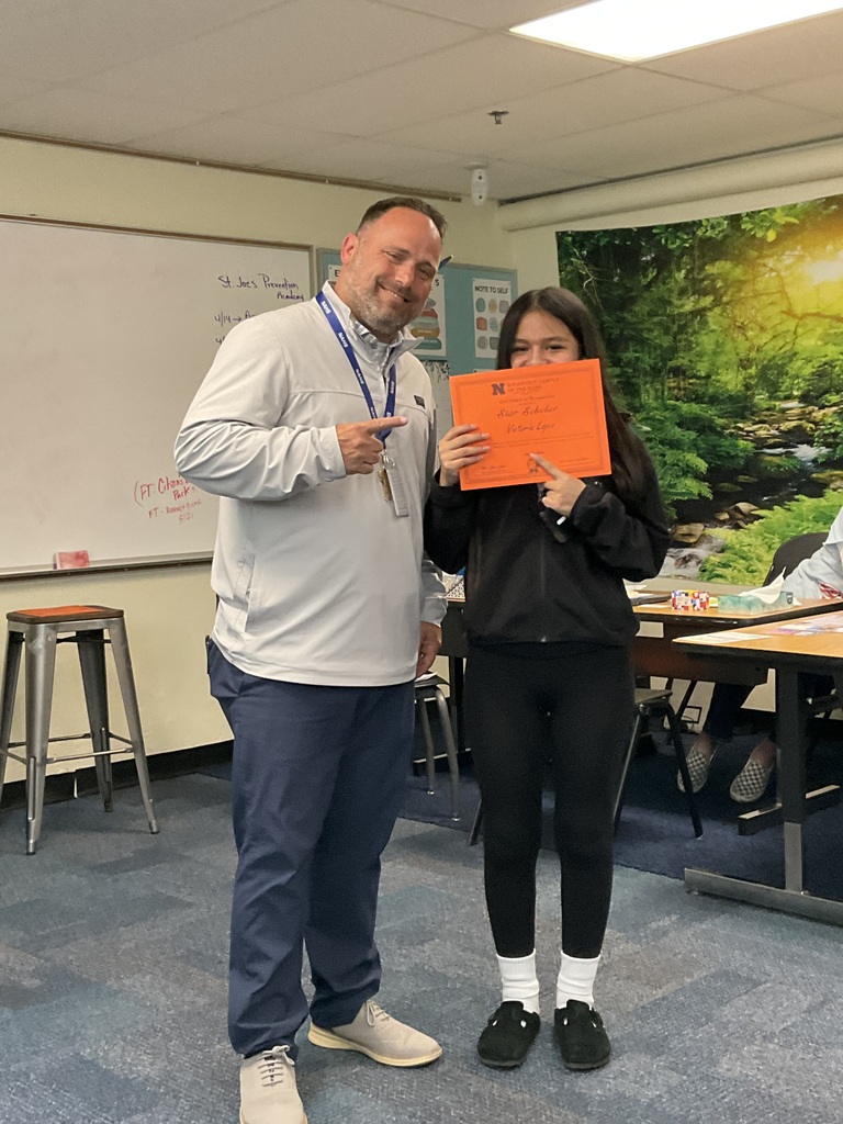 A student is posing with the principal with her award