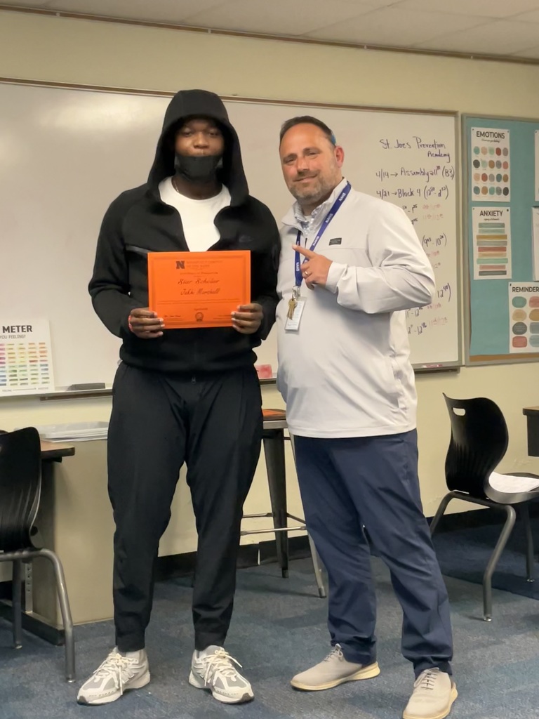 A student is posing with his award and the principal