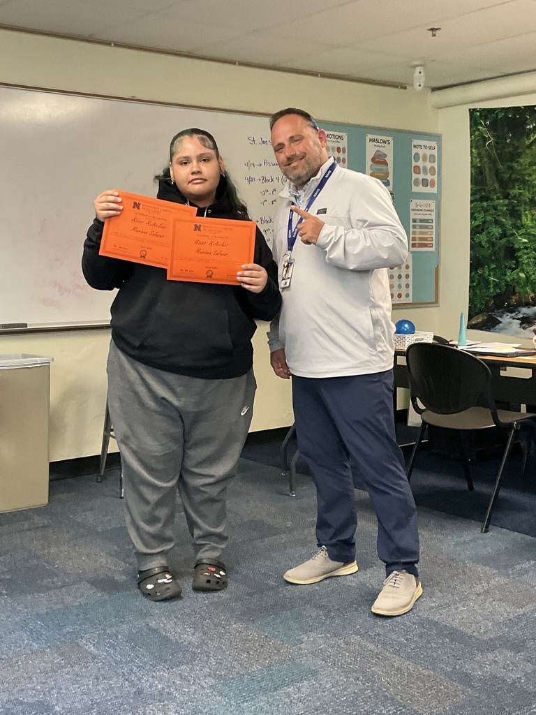 A student is posing with her award alongside of the principal