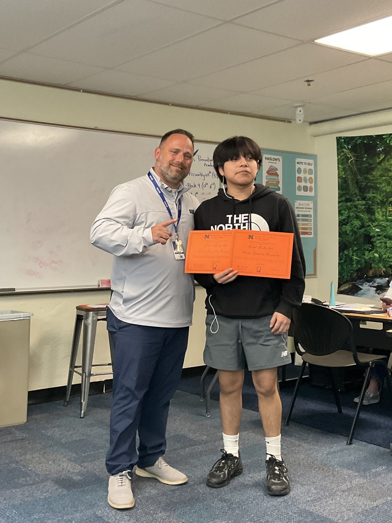 A student is posing with his award alongside of the principal
