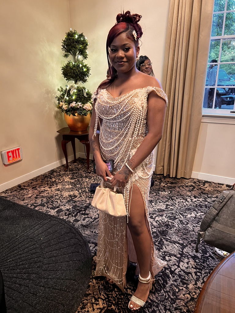 A female student is posing in the gown inside