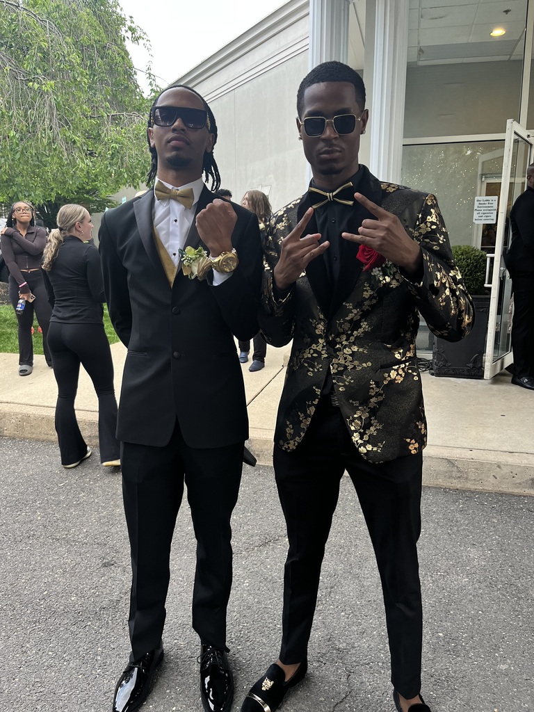 Two male students are posing outside in their prom gear