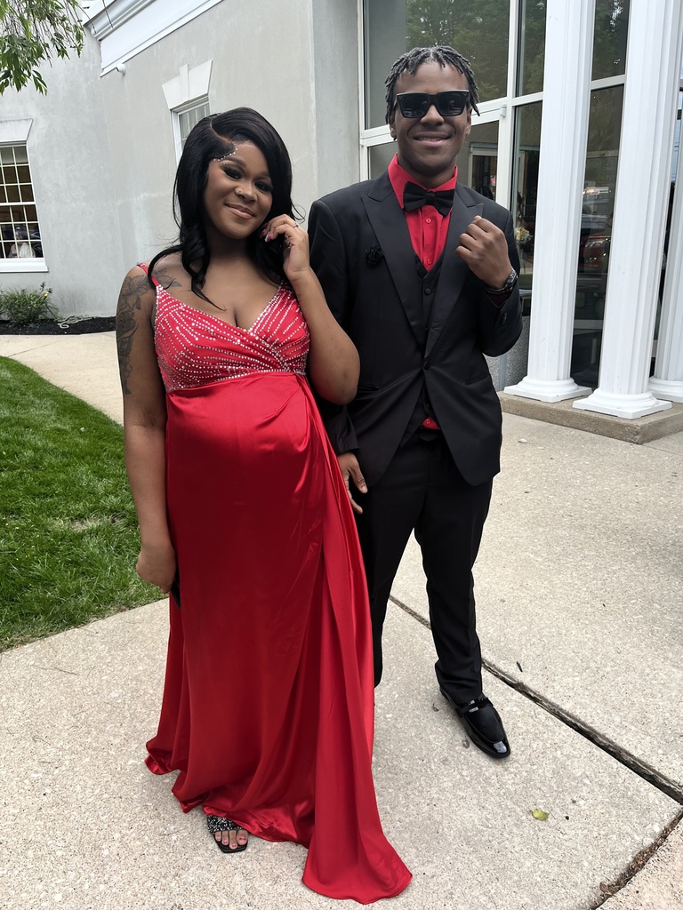 Two students are posing outside in their prom gear