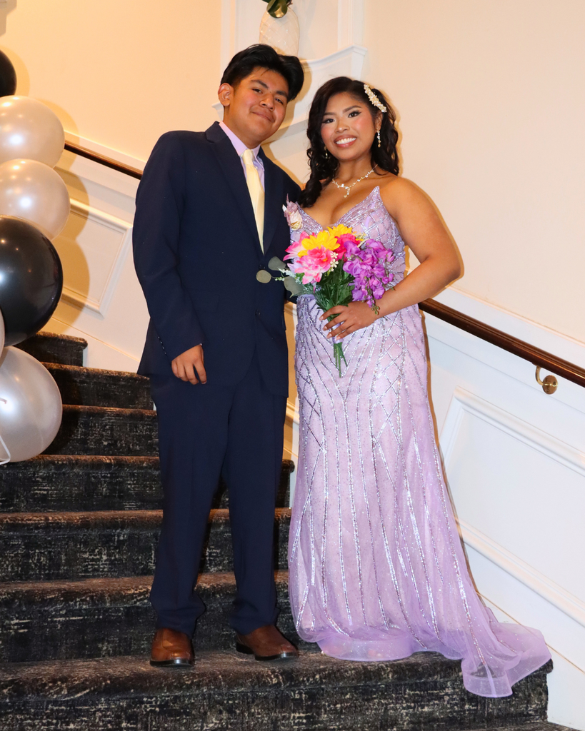 Two students pose for photo on staircase with balloons on the railings.
