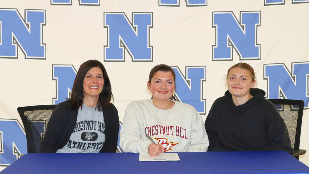 Senior student-athlete sitting at signing table with family.