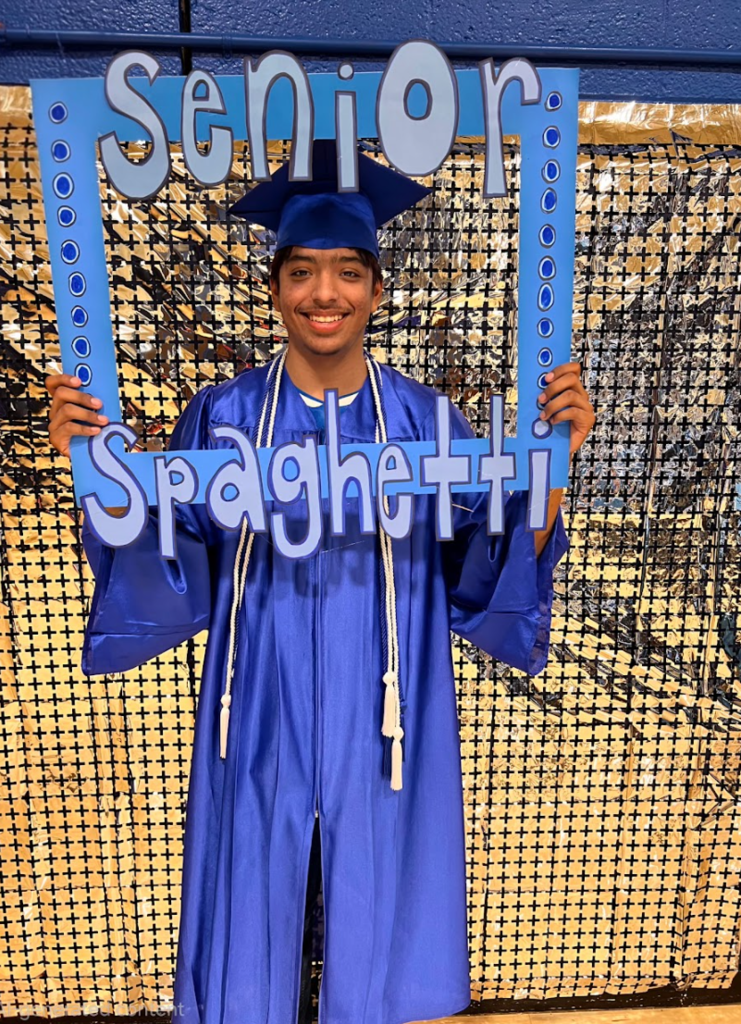 A senior is holding a sign for the senior spaghetti dinner