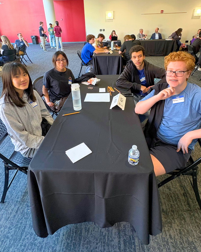 Four studnets sitting at table at Temple University competition.