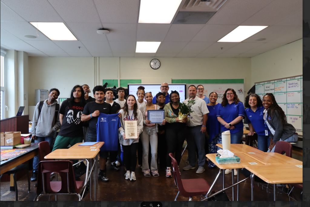 Students and administrators are standing around the teacher of the year