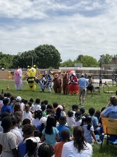 Teachers in inflatable costumes race at the field day assembly.