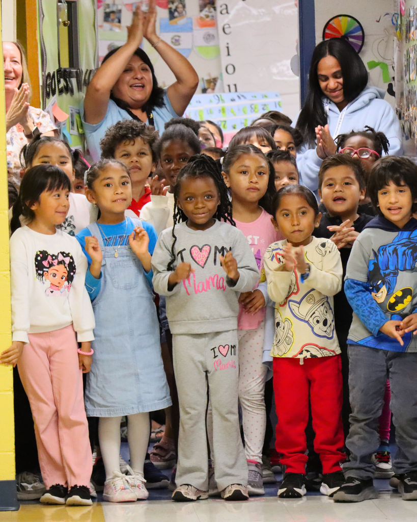 Students and teacher cheering and clapping from down the hallway.