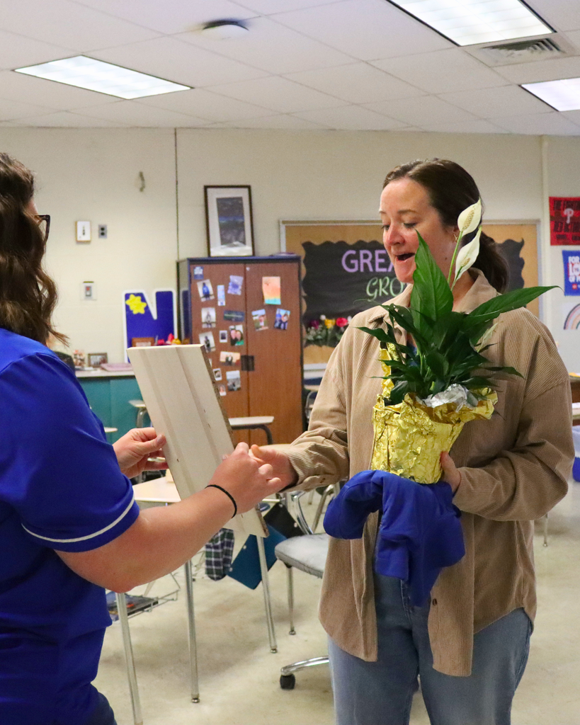 Mrs. Carmona receiving engraved plaque while holding flowers.