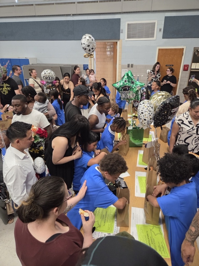 Fourth graders peek into their gift bags at their celebration.