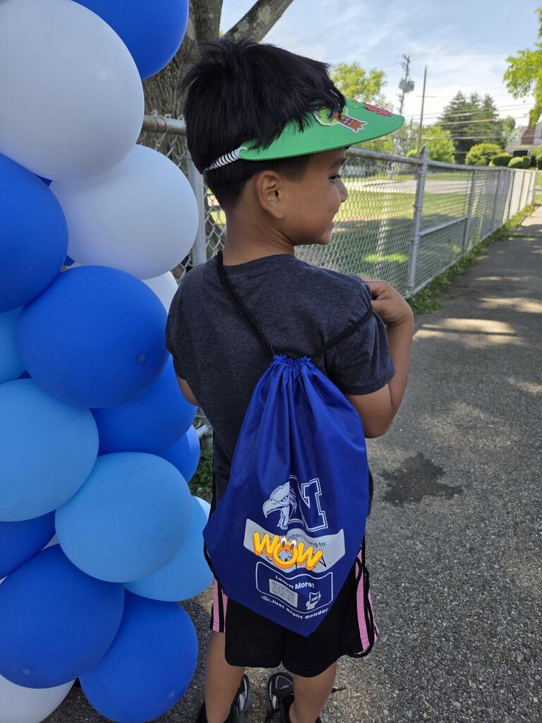 A student proudly shows his new bag of books.