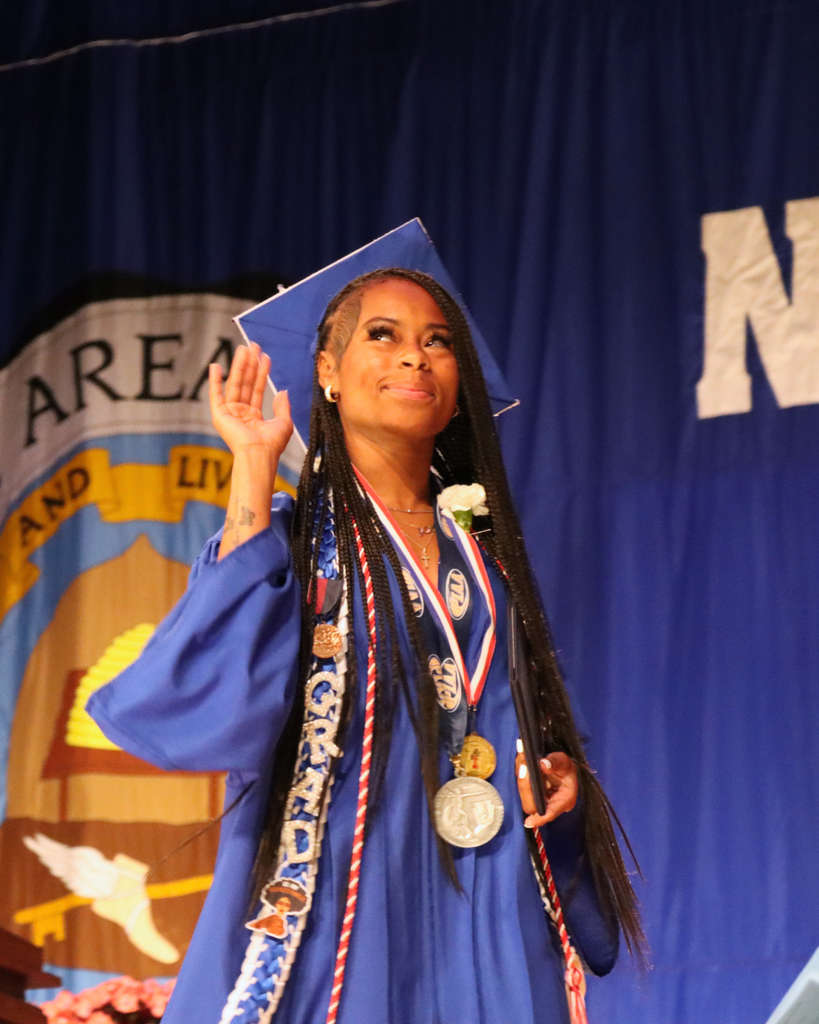 Graduate waving as they cross the stage.