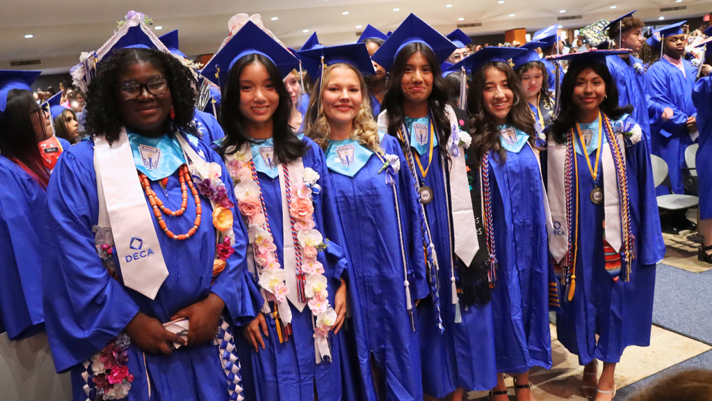 Six graduates pose for photo in the auditorium.