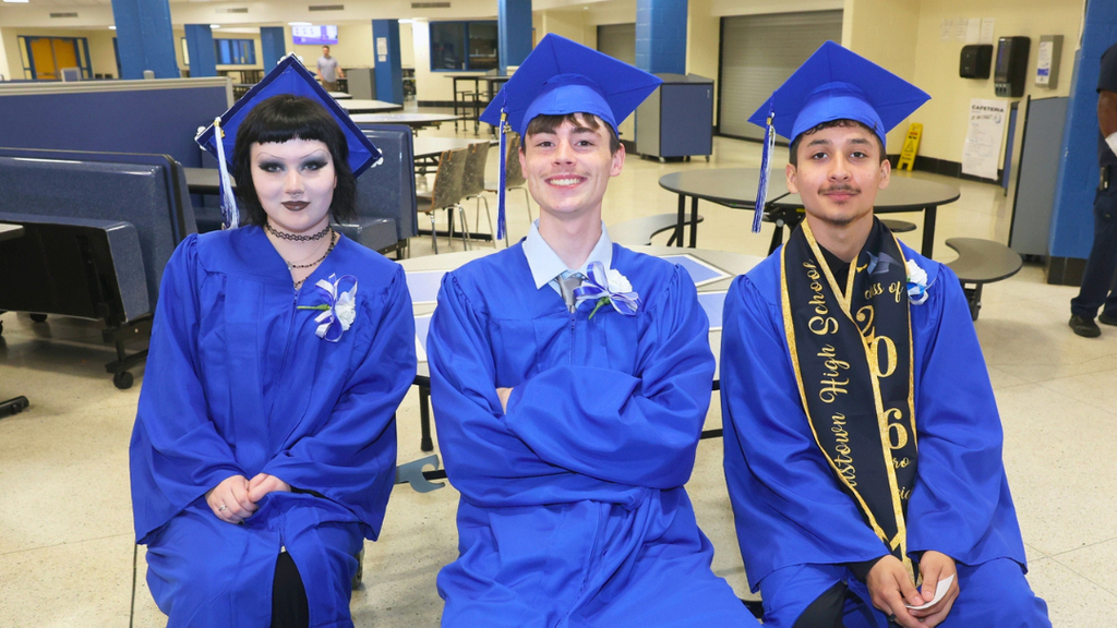 Three graduates in the NAHS cafe waiting to line up for graduation.