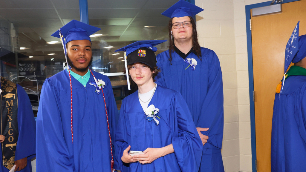 Three graduates pose for photo while waiting to line up for graduation.