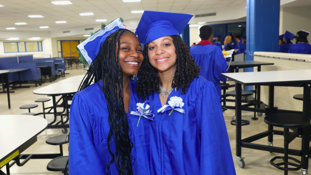 Two graduates pose for photo while waiting to line up for graduation.