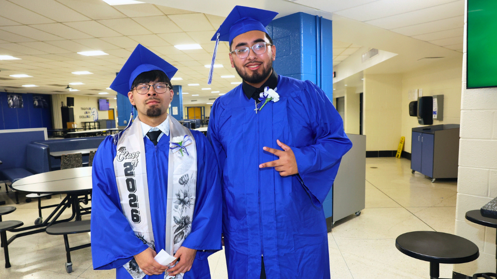 Two graduates pose for photo while waiting to line up for graduation.