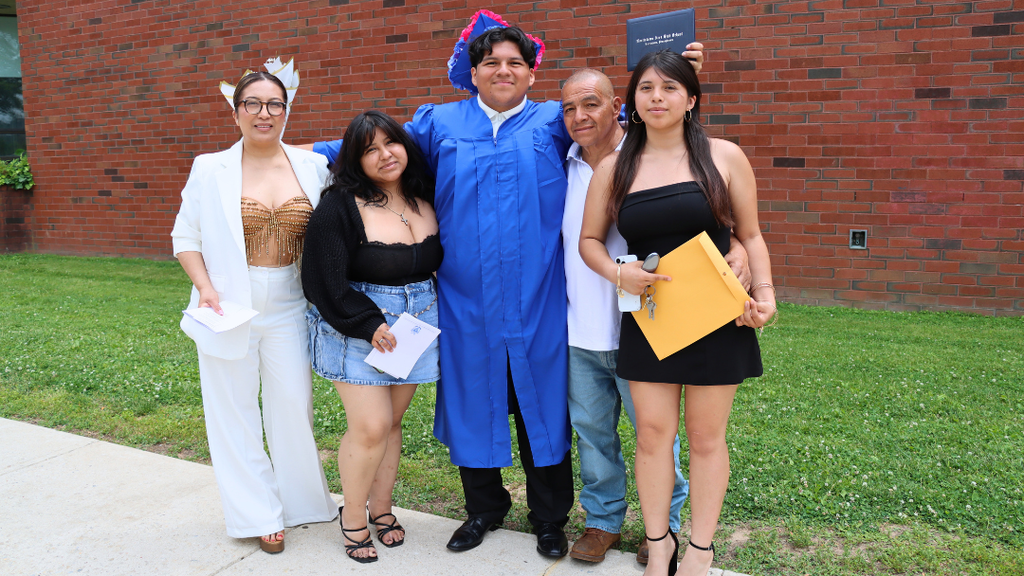 Graduate poses with their family outside after graduation.