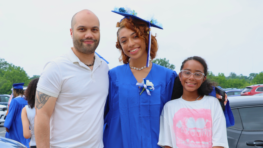 Graduate poses with their family outside after graduation.