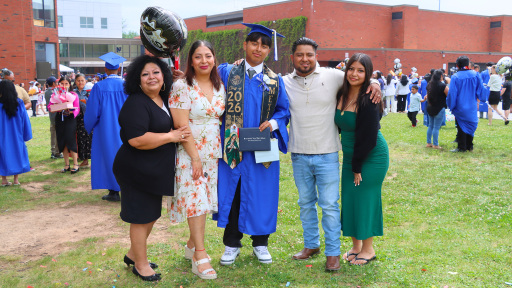 Graduate poses with their family outside after graduation.