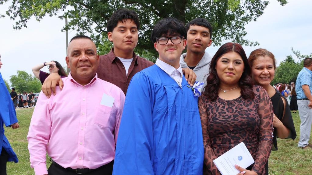 Graduate poses with their family outside after graduation.