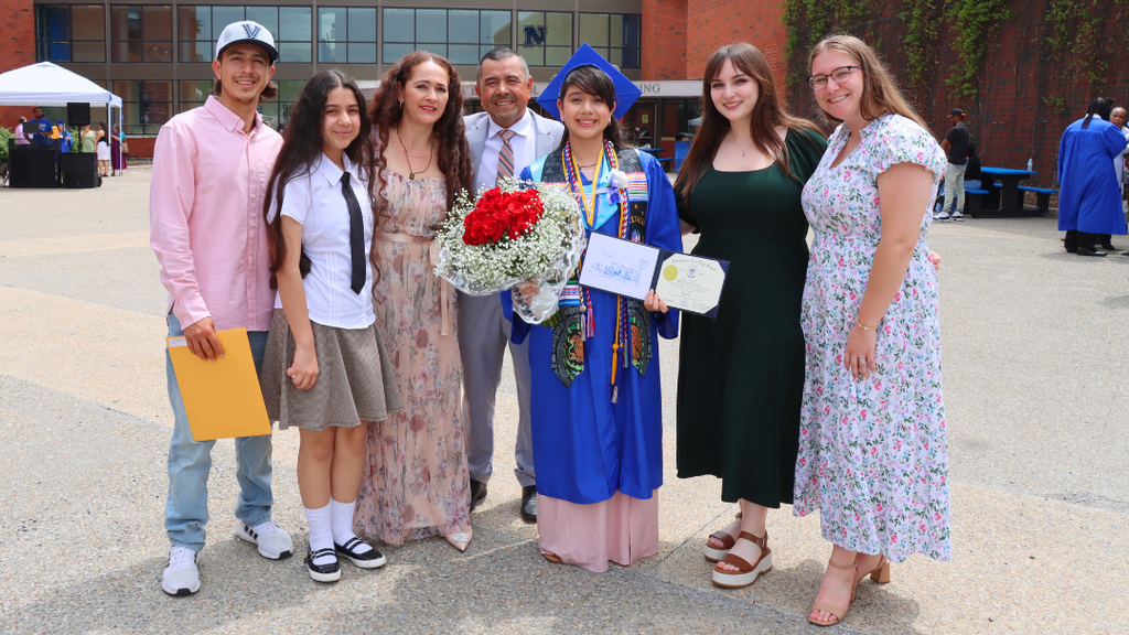 Graduate poses with their family and two teachers outside after graduation.
