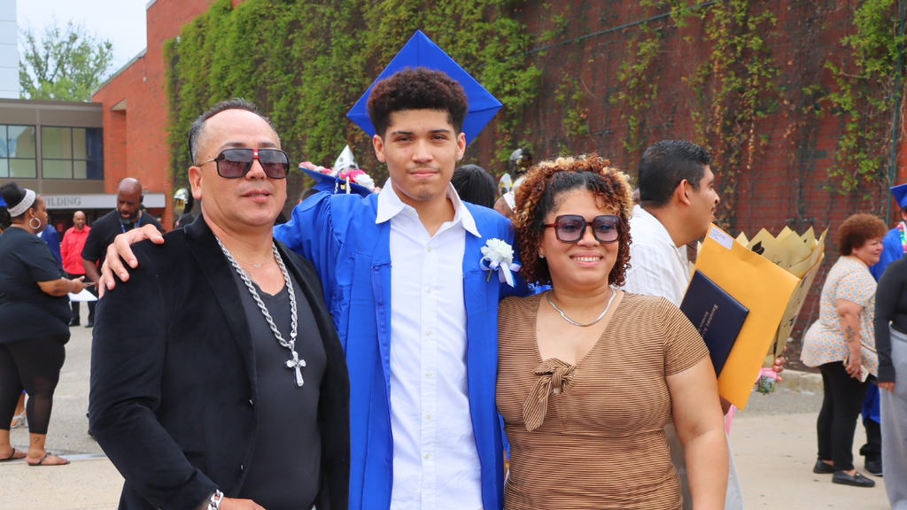Graduate poses with their family outside after graduation.