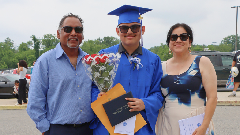 Graduate poses with their family outside after graduation.
