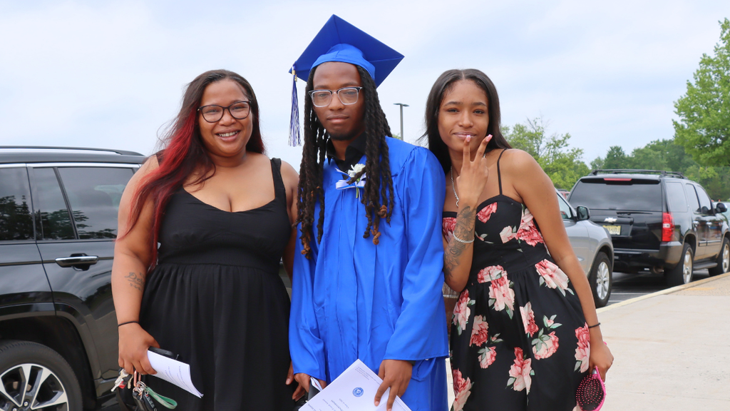 Graduate poses with their family outside after graduation.