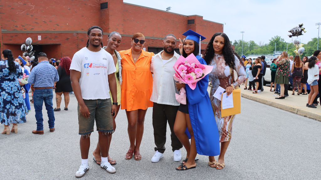 Graduate poses with their family outside after graduation.