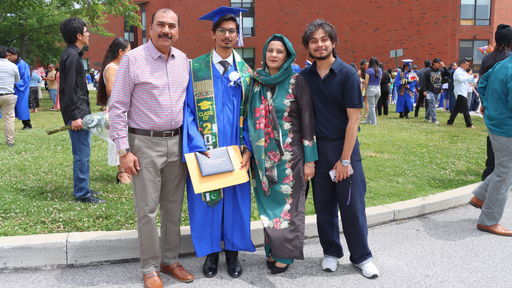Graduate poses with their family outside after graduation.