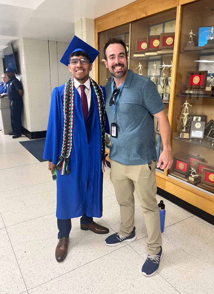 A teacher and a student are posing in a cap and gown 