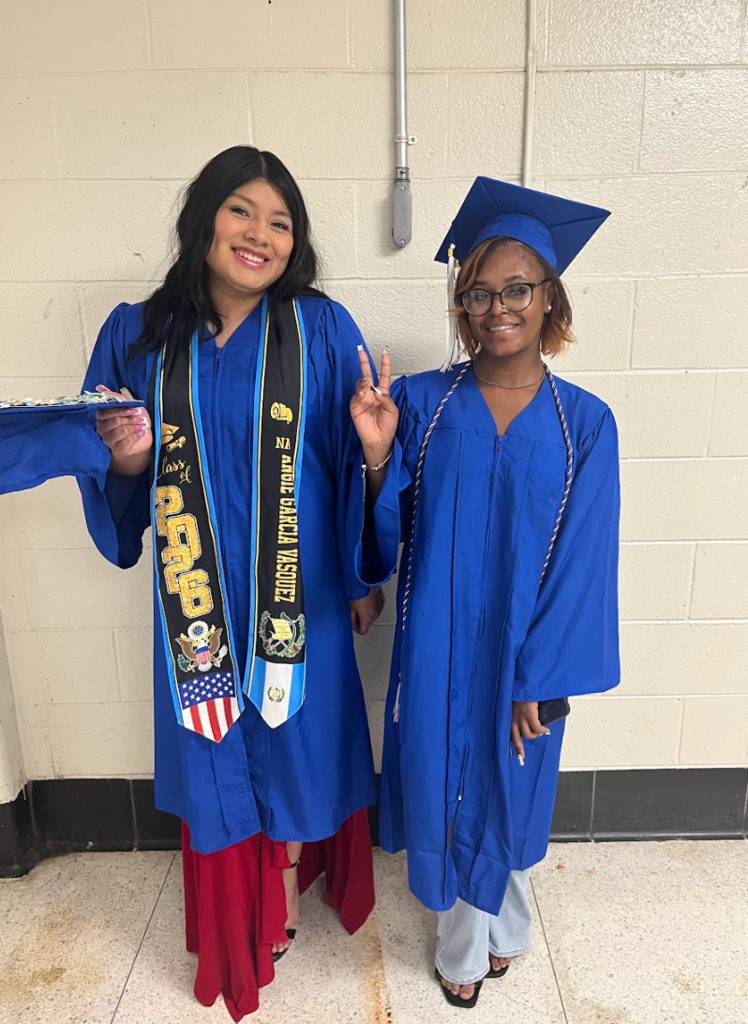 Students are posing in their cap and gowns at graduation 