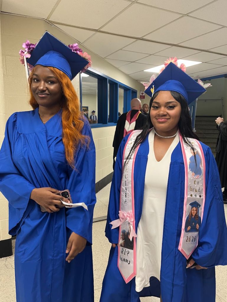 Two students are posing together in their cap and gowns