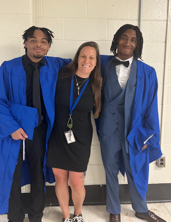 Two students and a teacher are posing together 