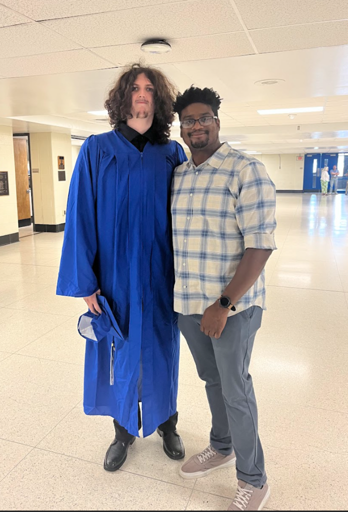 A photo of a teacher and student in his cap and gown 