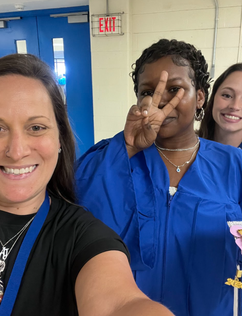 Teachers are posing with a student. 