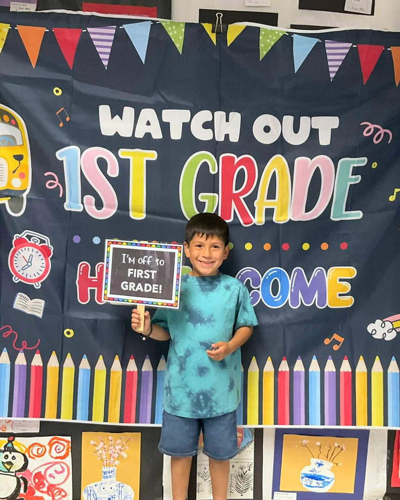 Student holds sign that says "I'm off to first grade!"