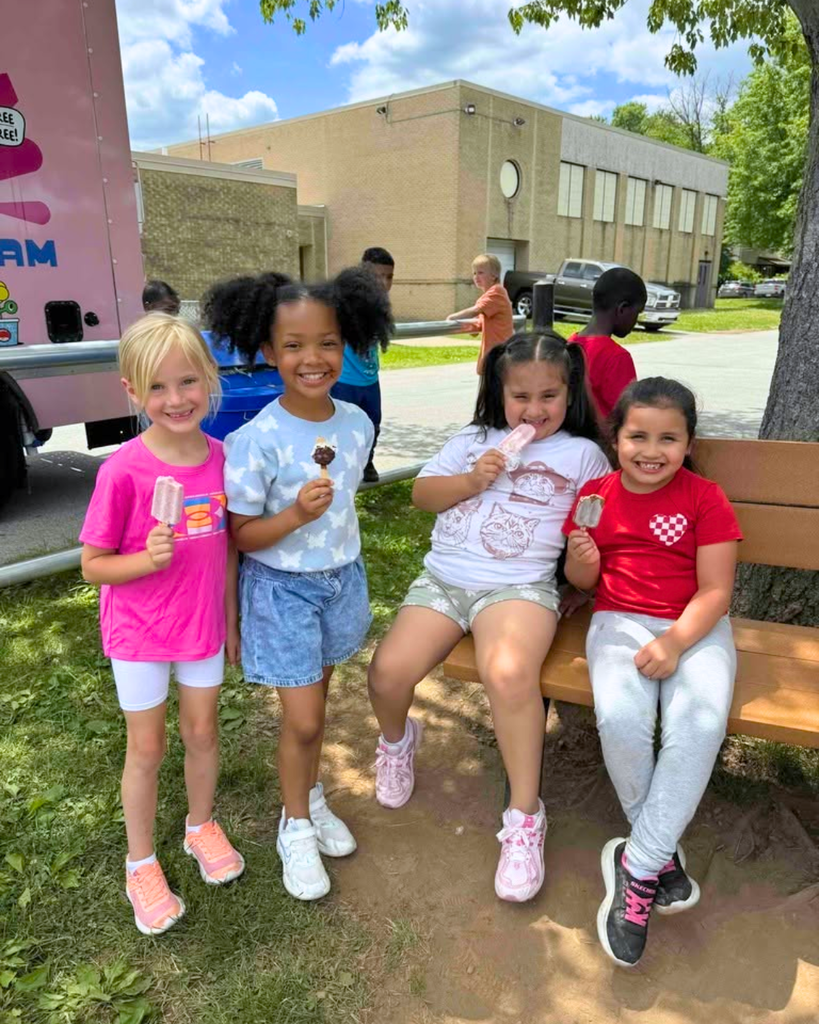 Four elementary students smile for photo with ice cream.