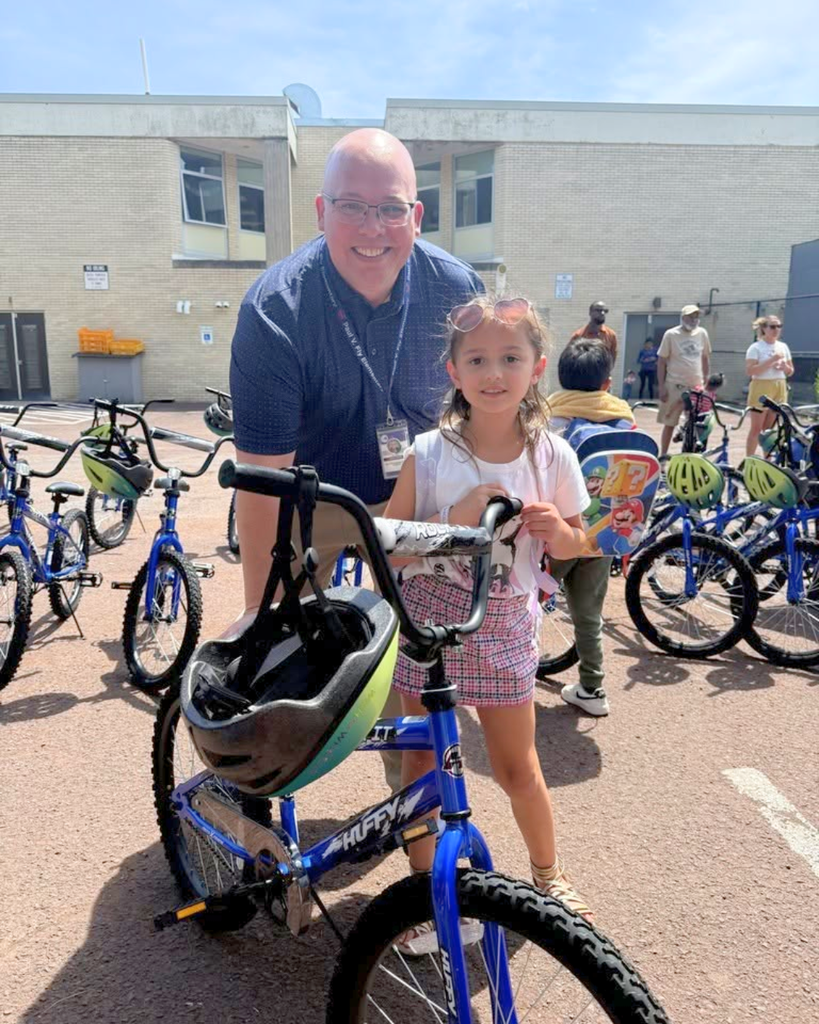 Adult poses for photo with student and their new bike.